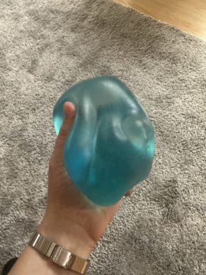 Finnegan's hand holds a blue blob, their current favorite stim toy, a "NeeDoh Jumbo Nice Berg" 